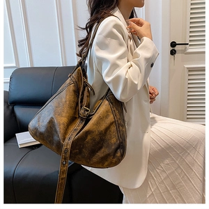 Detail of distressed brown faux leather texture and metallic eyelet strap on tote bag