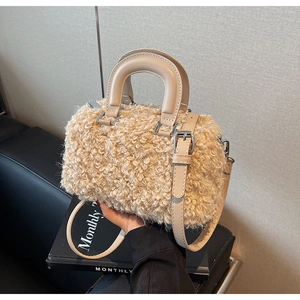 Detailed shot of beige plush Boston bag featuring silver metal clasps and leather handle