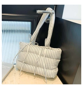 Détail du sac cabas matelassé avec nœud sur la bandoulière sur fond de marbre