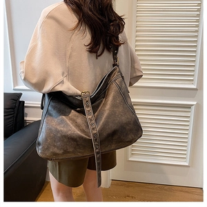 Detail of a large vintage washed PU leather shoulder bag with adjustable eyelet strap