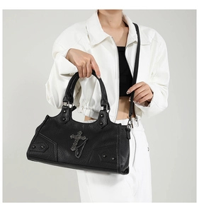 Detail der gotischen schwarzen Tasche mit Kreuzanhänger und Nieten auf Lychee-Leder