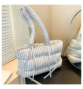 Détail d'un sac cabas matelassé à rayures bleues et blanches avec poignées à nœuds