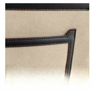 Detailed close-up of beige canvas texture with black leather trim and fine stitching