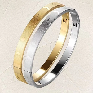 Close-up of gold and silver steel bangles featuring moon phase and cloud engravings