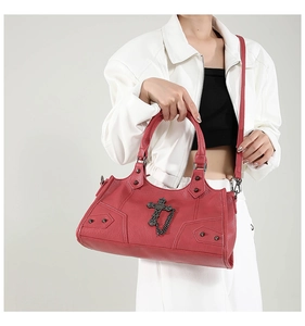 Detail der dunkelroten Punk-Handtasche mit silbernen Kreuzanhängern und Metallnieten