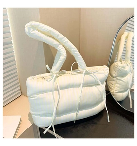 Détail du sac cabas matelassé à rayures jaune crème sur une surface en bois sombre
