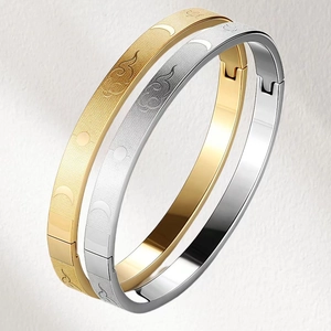 Detail of gold and silver stainless steel bangles with engraved celestial patterns