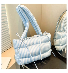 Détail du sac matelassé à rayures bleues et blanches avec un nœud décoratif élégant