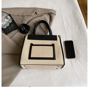 Flat lay of canvas handbag with leather trim, featuring a shoulder strap and accessories