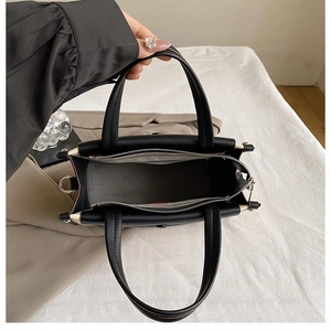 Interior view of black tote bag showing gray lining, zipper pocket, and D-ring hardware