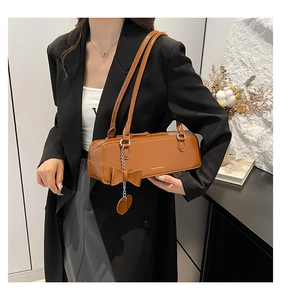 Detail of a brown glossy leather shoulder bag featuring a chic bow and gold lettering
