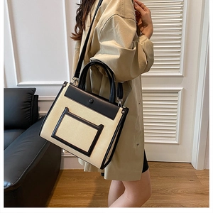 Detailed view of bicolor canvas tote bag paired with a beige trench coat for a chic look