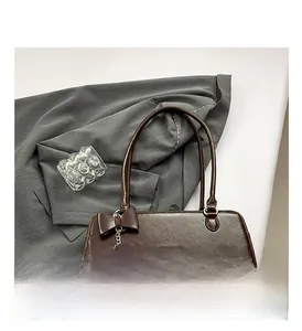 Detail of dark brown baguette bag with bow decoration and heart charm accessory