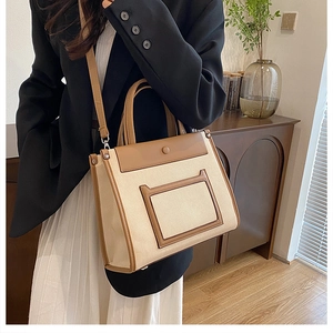 Detailed view of a canvas and leather tote bag worn as a crossbody bag for daily styling