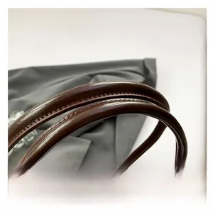 Detail of the brown leather shoulder bag showing the sturdy stitching and rounded handle