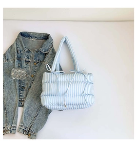 Détail d'un sac cabas matelassé à rayures bleues et blanches avec un nœud décoratif