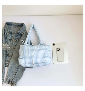 Détail du sac matelassé à rayures bleues avec poignée à cordon nœud et texture douce