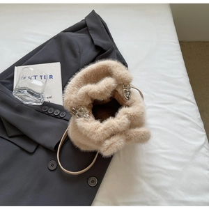 Detail of beige faux fur bucket bag with heart metal ring and brown fabric lining