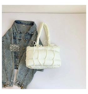 Gros plan d'un sac cabas matelassé avec des nœuds en ruban sur une veste en jean