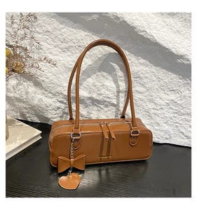 Detail of caramel brown PU leather shoulder bag with silver double zippers and bow charm