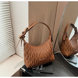 Detailed view of brown pleated hobo bag featuring decorative side bow and zip closure