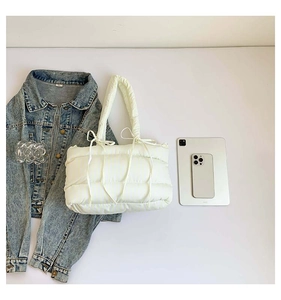 Vue détaillée de dessus d'un sac cabas matelassé crème avec tablette et veste en jean