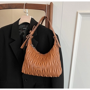 Macro detail of brown pleated leather hobo bag with signature bow and textured finish