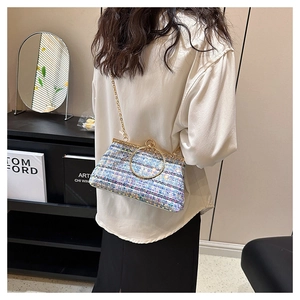 Chic tweed clutch bag with sequins and large gold ring handle worn by model