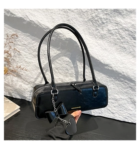 Glossy black baguette bag with gold lettering and delicate heart bow charm detail