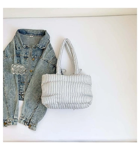 Détail d'un sac cabas matelassé à rayures bleues avec des poignées souples