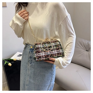 Detail of colorful sequin handbag with gold ring handle and metal chain strap in use