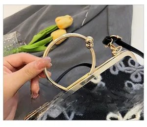 Détail de broderie florale sur sac de soirée en tricot noir avec poignée dorée ronde