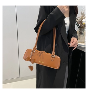 Brown leather baguette bag with heart pendant shown on model in French style