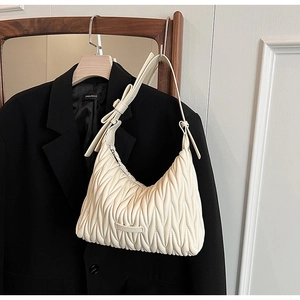 Detail of cream pleated leather underarm bag with bow decoration and metal logo