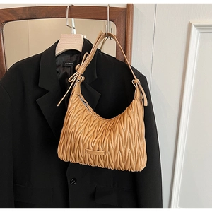 Detail of camel quilted pleats texture on a crescent shoulder bag with leather strap