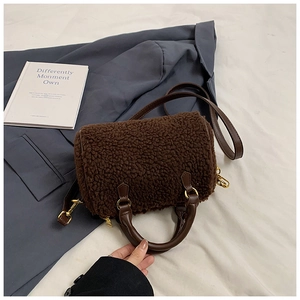 Detailed view of dark brown teddy fleece barrel bag with faux leather strap and golden hardware