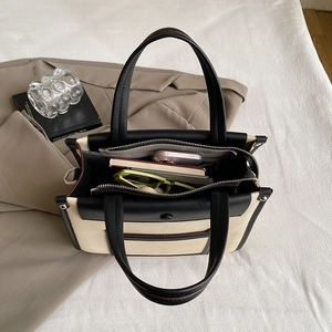 Canvas and black leather tote bag with interior compartments for laptop and phone