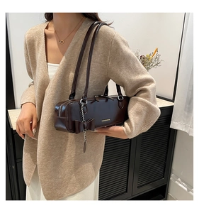 Detail of dark brown leather underarm bag with bow charm and dual strap handles