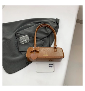 Size comparison of a brown baguette bag with phone on a white minimal background