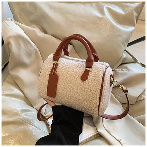 Detail der flauschigen cremeweißen Boston-Tasche mit braunen Lederriemen und Metallhaken