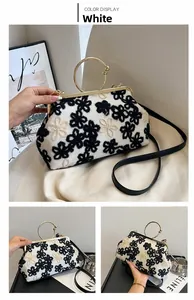 Gros plan sur l'embrayage blanc avec broderies florales noires et poignée dorée chic