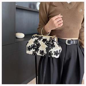 Détail du sac de soirée en tricot avec broderie florale et fermoir en métal doré