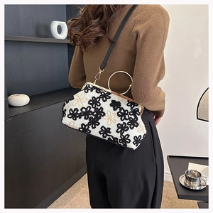 Détail du sac bandoulière élégant avec broderie florale et poignée en anneau doré