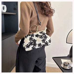 Détail de broderie fleurie sur sac vintage avec poignée ronde en métal doré