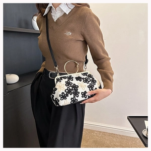 Détail de la broderie florale sur le sac à bandoulière en coquillage avec anneau doré