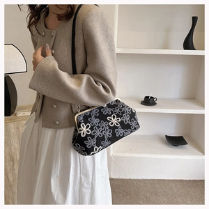 Détail d'un sac bandoulière noir brodé de fleurs avec cadre métallique doré élégant