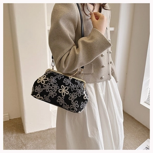 Détail du sac tricoté vintage avec broderie florale grise et cadre en métal doré