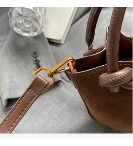 Close-up of brown suede bucket bag featuring premium leather handle and vintage gold hardware