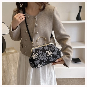 Détail d'une pochette brodée de fleurs avec poignée ronde dorée et fermoir rétro chic