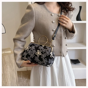 Détail de la broderie florale sur pochette de soirée noire avec poignée anneau doré